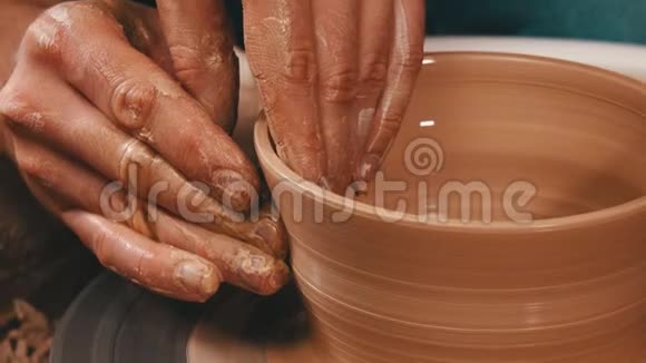 人类的双手在陶工轮上从陶土中雕刻出侧面视频的预览图