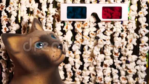 猫雕像看着3D眼镜爆米花和金色闪闪发光的金属圈的动态背景离焦视频的预览图