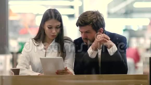 商务夫妇在喝咖啡休息时使用平板电脑视频的预览图