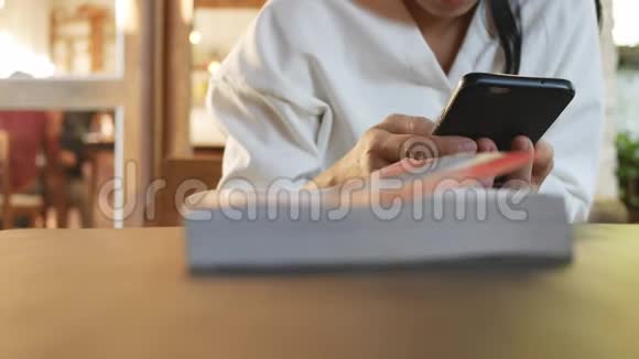 漂亮的年轻女人在咖啡馆里坐在木椅上放松和使用智能手机视频的预览图