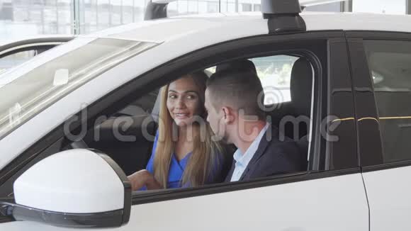一对漂亮优雅的夫妇坐在经销商的新车里视频的预览图