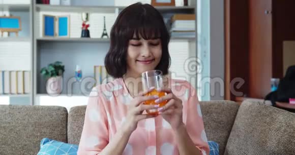 在沙发上喝橙汁的亚洲年轻美女视频的预览图