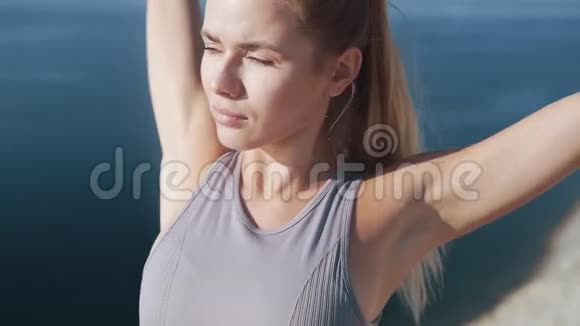 女人的肖像在日出时做伸展运动在背景下看海景视频的预览图