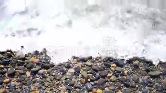 海浪拍打海滩巨石五彩缤纷阳光明媚的早晨视频的预览图