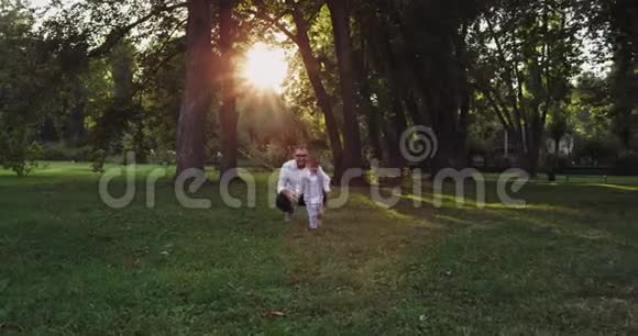 在令人惊叹的绿色公园里和爸爸一起跑着小可爱的男孩他们玩得很可爱视频的预览图