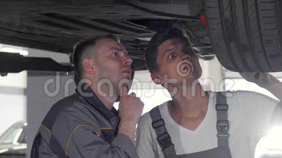 两名汽车机械师在车库检查一辆汽车的悬挂情况视频的预览图