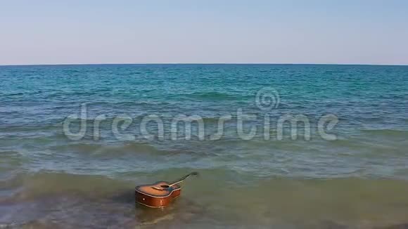 吉他在水中漂浮游泳漂移在海洋或海洋中波浪波浪把吉他扔在岸上或海滩上空中景观视频的预览图