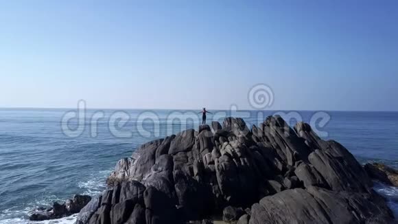 女人的剪影在波浪中的悬崖上沉思视频的预览图