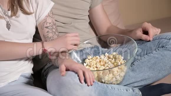 年轻夫妇坐在客厅里看电视吃爆米花特写视频的预览图