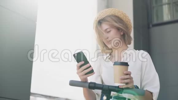 女人使用智能手机骑电动踏板车后喝咖啡视频的预览图