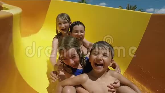 快乐的孩子们在水上乐园里滑下滑梯视频的预览图