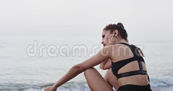 充满魅力和疲惫的年轻女子在海滩上锻炼后看着大海冥想视频的预览图
