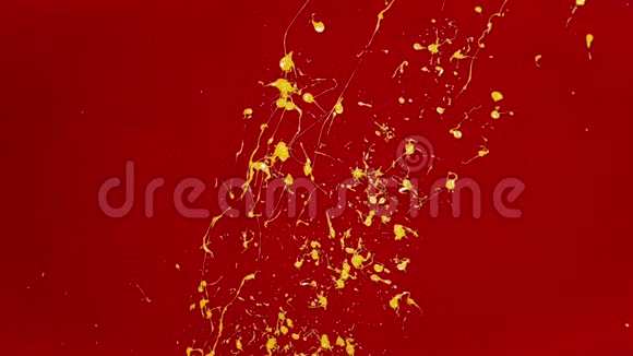 一个人用刷子在红墙上溅出亮黄色的油漆视频的预览图