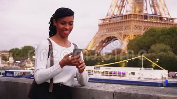 站在巴黎堤岸上用智能手机看照片的年轻女子视频的预览图