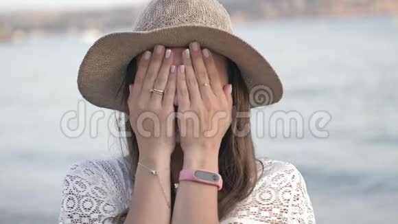 年轻的女人戴着帽子睁开眼睛她惊讶海背景兴奋有趣快乐的女孩慢慢视频的预览图