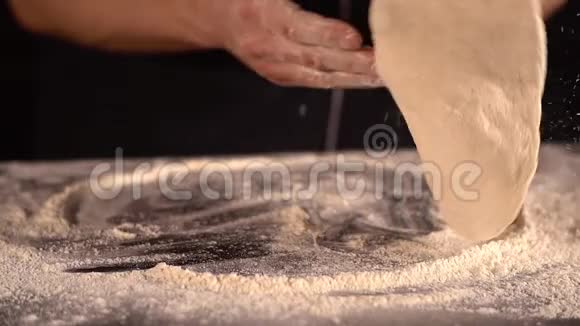 披萨师用面粉把面团扔到桌子上揉成披萨面团男人的手面粉视频的预览图