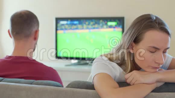 一个被冒犯的女人坐在一个看电视游戏的男人旁边视频的预览图