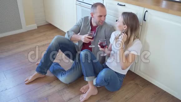 幸福多情的一对说喝酒的夫妇坐在厨房的地板上视频的预览图