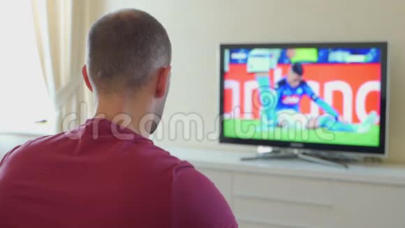 紧张的男人在电视上看比赛结果高兴后视视频的预览图