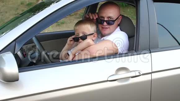 父子俩戴着墨镜车里穿着白色t恤慢动作视频的预览图