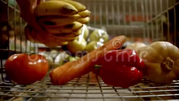 购物手推车在商店里选择物品购买水果和蔬菜并将它们添加到手推车中视频的预览图