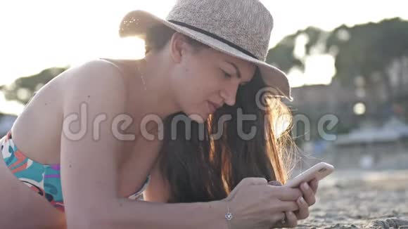 一个女人在海滩上用智能手机发短信背景是大海视频的预览图