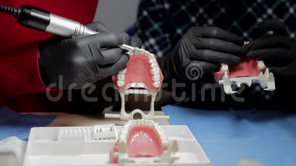 两个实习牙医戴着黑色手套拿着一个男人的下巴模拟UPS练习人的下巴模型视频的预览图