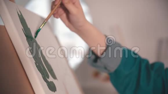 一位年轻女子在艺术工作室的画布上一幅绿色的手画视频的预览图
