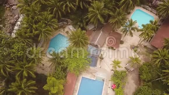 热带度假酒店的鸟瞰蓝色游泳池提供有室外游泳池和棕榈的Drone观景旅游酒店视频的预览图