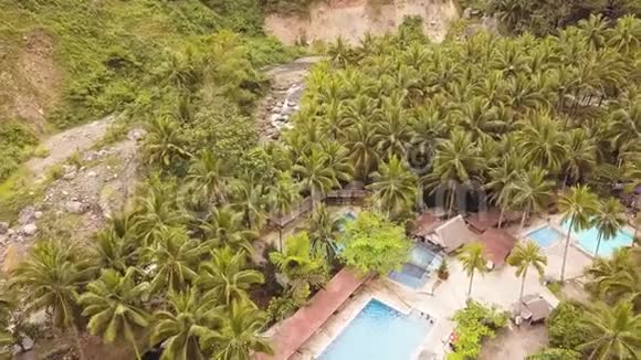 热带度假酒店绿色棕榈树从上面的飞行无人机男子游泳在蓝水游泳池度假视频的预览图