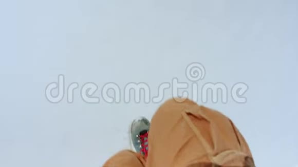 穿着橙色裤子和蓝色靴子的男人在雪地上行走视频的预览图