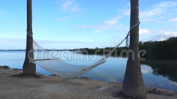 在海边的热带海滩棕榈树下的浪漫舒适吊床视频的预览图