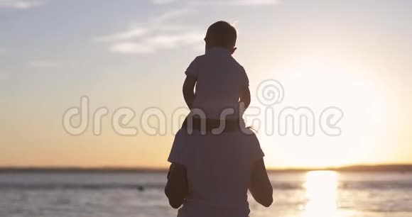 一个小男孩坐在他母亲的肩膀上背景是夕阳视频的预览图