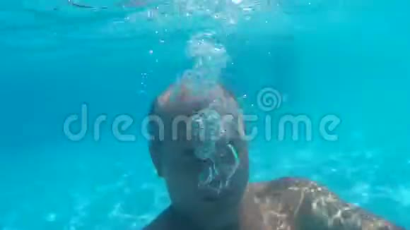 秃头男子潜水水下游泳池和吹气泡水下观景人吹着透明的气泡视频的预览图