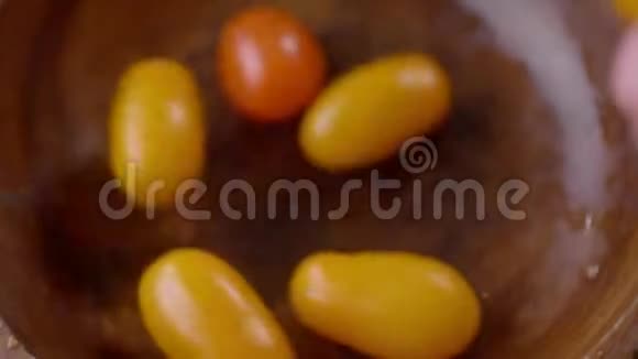 黄色和红色的樱桃番茄放在一个木碗里慢慢落下视频的预览图