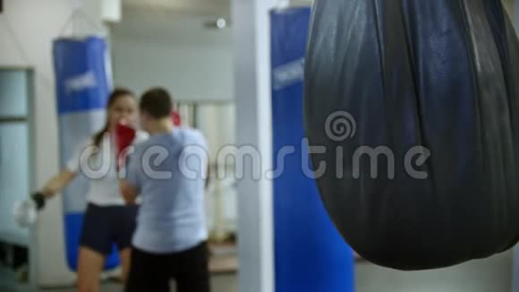 一对男女在体育馆练拳击拳击袋挂在前景视频的预览图