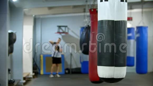 一个挂在健身房的拳击袋男人用绷带包扎他的手视频的预览图