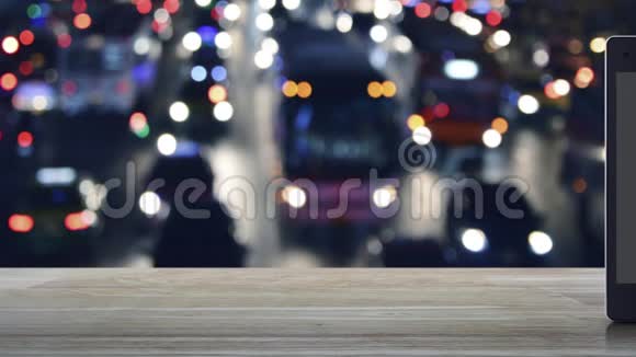 下载现代智能手机屏幕在木桌上的平面图标在城市w的模糊多彩夜光交通堵塞街道上视频的预览图