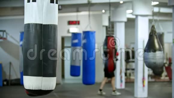 一个拳击袋挂在健身房男子拳击手走在后台视频的预览图