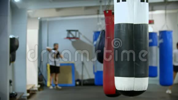 一个拳击袋在健身房的侧面悬挂男子用绷带包扎他的手视频的预览图