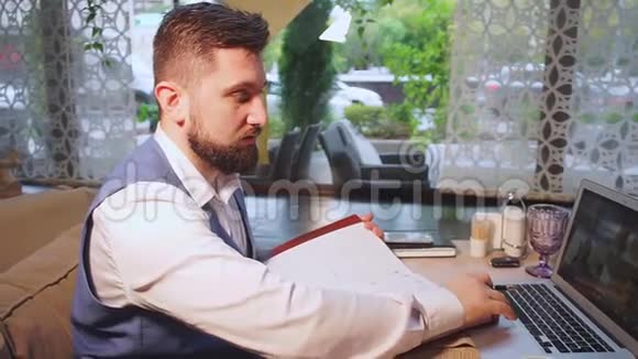 穿蓝色背心的商人喝咖啡做笔记视频的预览图