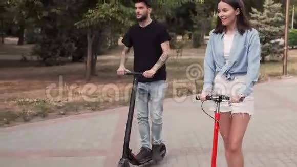 女孩和她的男朋友在一个城市公园里骑着一辆电动滑板车互相交谈视频的预览图