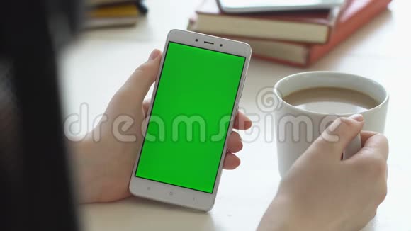 查看女士手持色度键绿色屏幕智能手机观看内容无需触摸或滑动喜欢喝酒视频的预览图
