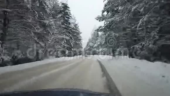 白雪覆盖了冬天的森林透过汽车的挡风玻璃看到了公路视频的预览图