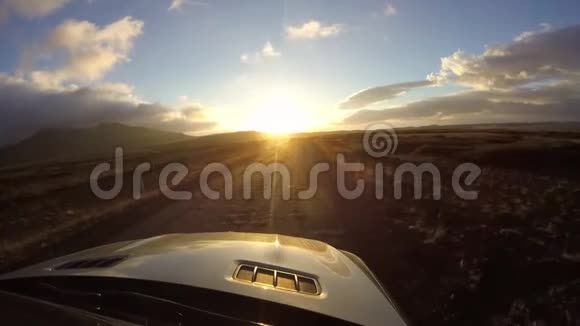 雄伟的汽车坐骑第一人坡在肮脏的乡村道路上疾驰傍晚日落沙漠山岭风景视频的预览图