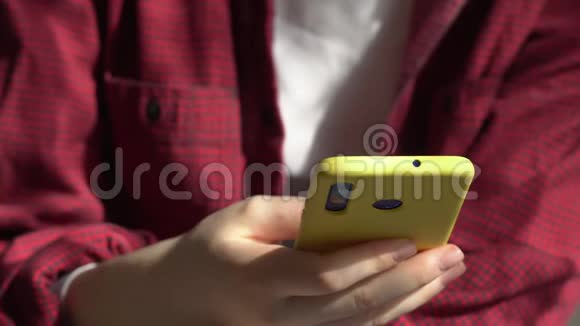 年轻的希普斯特女人演奏尤库莱吉他一个女人在智能手机上读一首歌4K视频的预览图