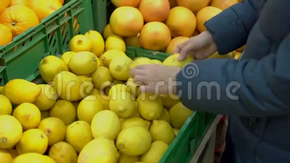 一个成年女孩在商店里选择黄色柠檬然后把它们放进玻璃纸包里超市里的顾客概念视频的预览图