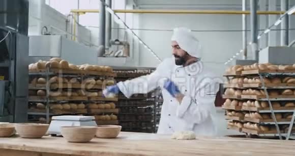 有魅力的面包师在一家大面包店工作时留着胡子边跳舞边拿着面团穿上视频的预览图