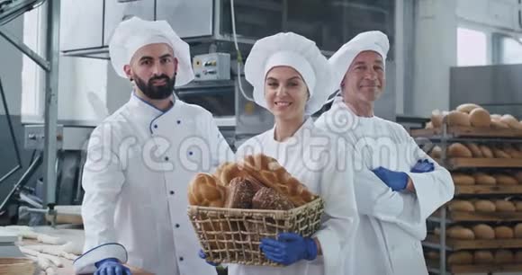 漂亮的女人笑容满面面包师和她的同事们穿着白色制服站在大个子旁边视频的预览图