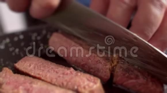 美味可口的大理石牛排切成薄片厨师一只手拿着牛排另一只手切在那里视频的预览图